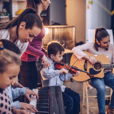 Children playing musical instruments in a cozy room with an instructor.