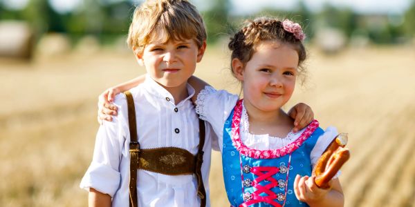 Two children in traditional Bavarian clothing outdoors.