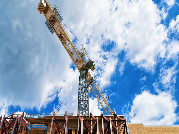 Tower crane at a building construction site under a blue sky.