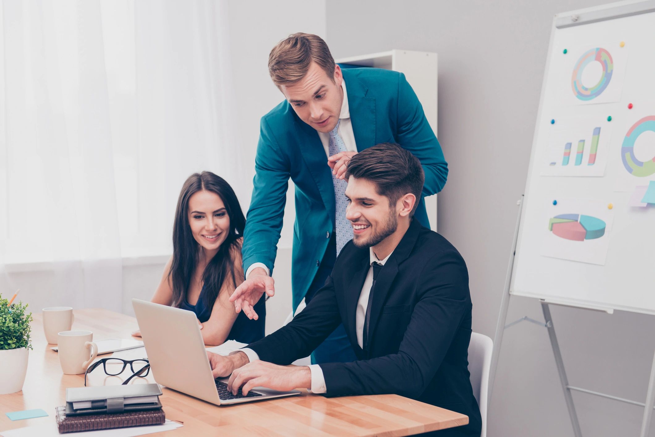 Consultant coaching two colleagues through an AI workflow on a laptop