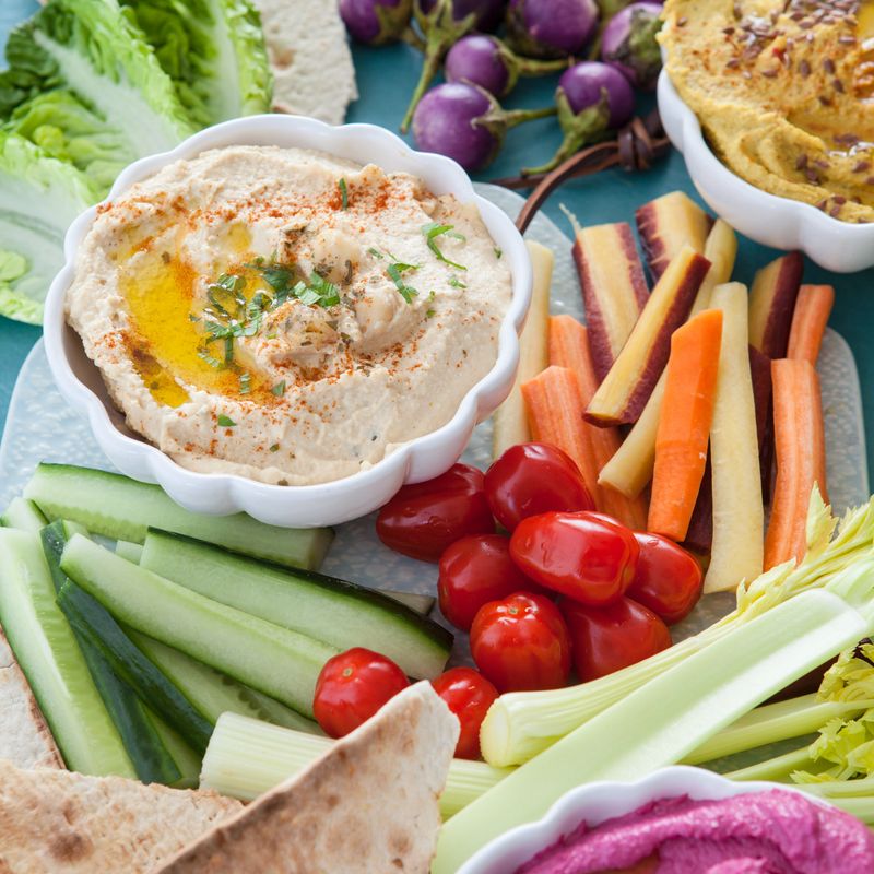 Variety of homemade hummus with fresh vegetable sticks