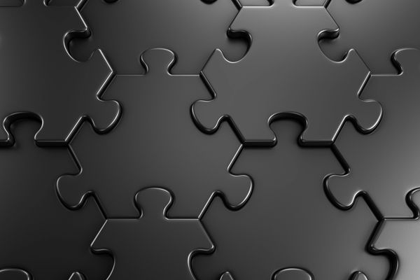 Close-up of black puzzle pieces fitting together.