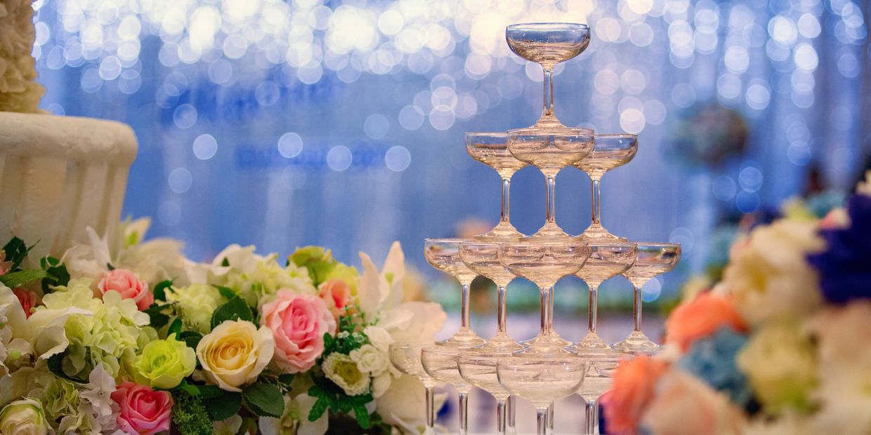 Elegant champagne tower surrounded by colourful flowers and soft bokeh lights.