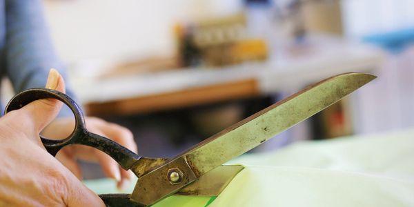 A person cutting fabric with large scissors.