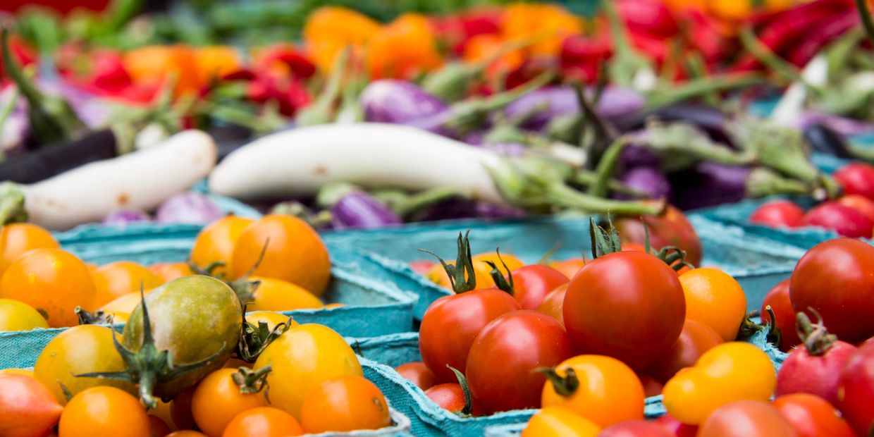 Colorful cherry tomatoes in blue cartons at a market.