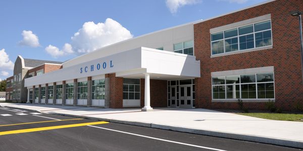Modern school building with brick and white exterior under a blue sky.