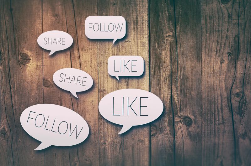 Paper cut speech bubbles with social media concepts on wooden background