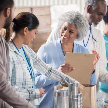 Volunteers packing canned goods and organizing items in a community service setting.