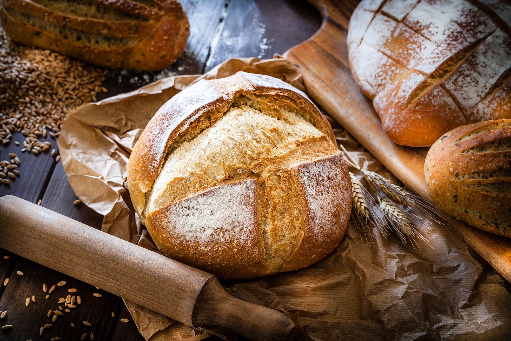 Freshly baked rustic bread with wheat grains and rolling pin.
