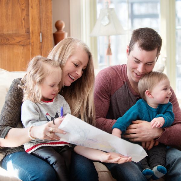 A happy family enjoying drawing time together on the couch.