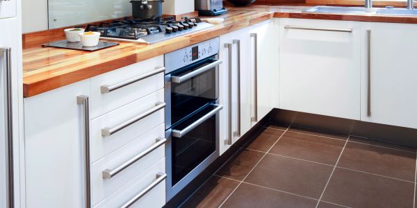 Cozinha moderna com armários brancos e bancada de madeira.