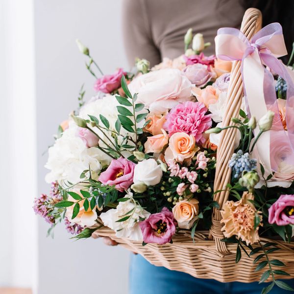A colorful basket of mixed flowers with a pink ribbon bow.