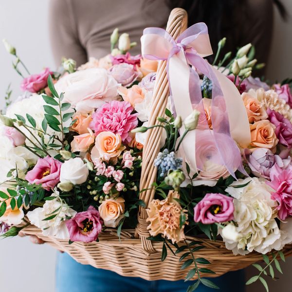 A colorful basket of mixed flowers with a pink ribbon bow.
