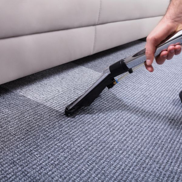Hand cleaning carpet with vacuum wand.