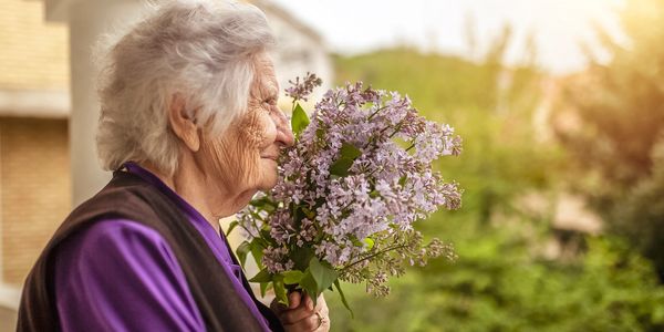 Woman smiling while smelling lilac flowers