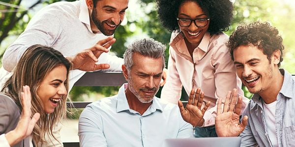Group of diverse coworkers happily engaging around a laptop.