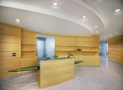 Modern reception area with wooden shelves and glass desk.