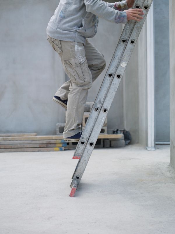 Person climbing a ladder in a construction area.