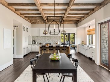 Modern dining area with dark wood table and rustic ceiling beams.