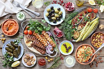 A colorful Mediterranean feast with grilled meats, vegetables, dips, and olives.