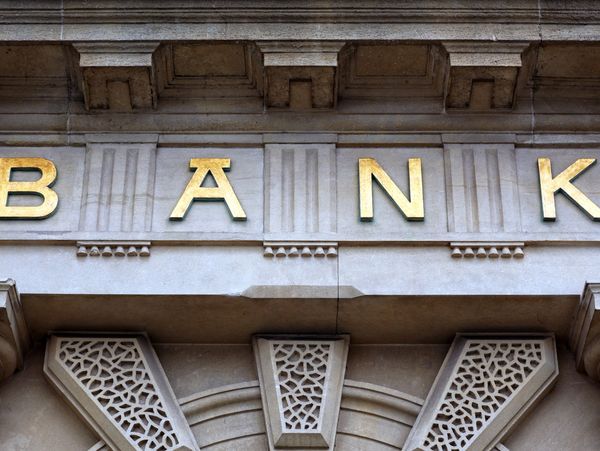 Golden letters spelling BANK on a stone building facade.