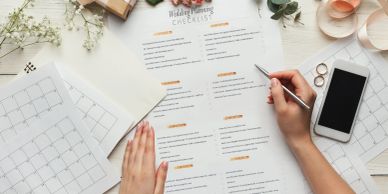 Person working on wedding planning checklist at a desk.