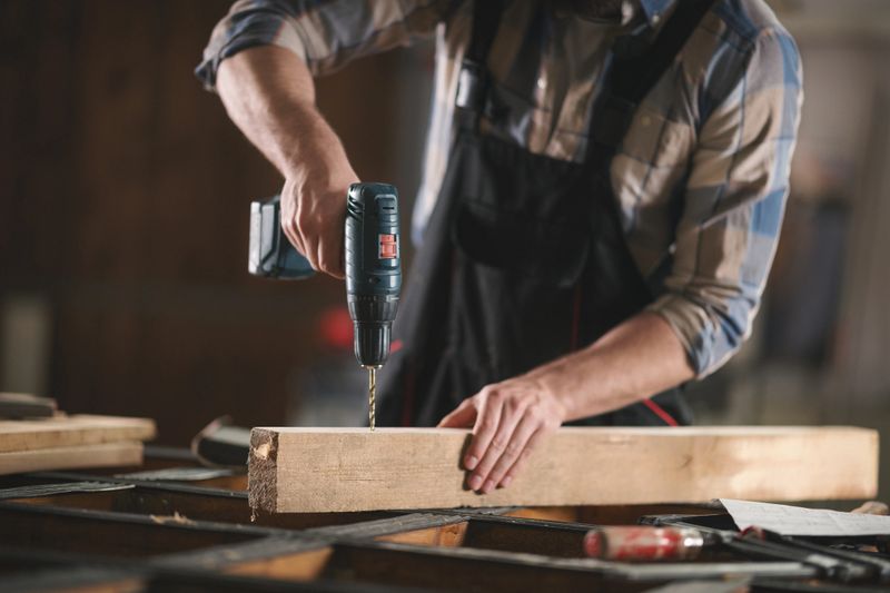 Young carpenter working with wood. Shallow DOF. Developed from RAW; retouched with special care and attention; Small amount of grain added for best final impression.16 bit Adobe RGB color profile.