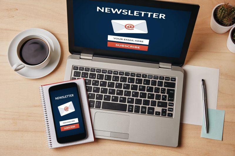 Subscribe newsletter concept on laptop and smartphone screen over wooden table. All screen content is designed by me. Flat lay