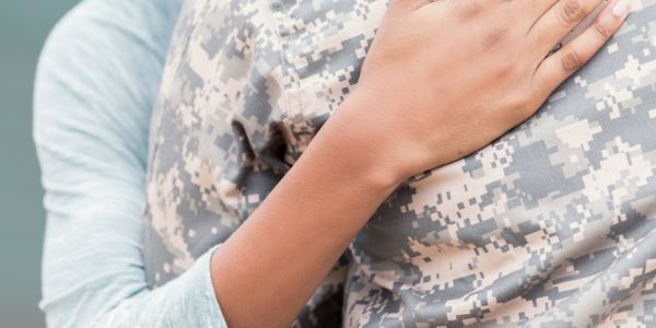 A person embraces someone in military uniform, showing support and care.