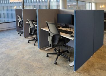 Modern office cubicles with ergonomic chairs and computer monitors.