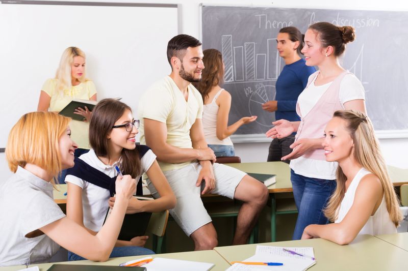 Several happy young students communication sitting in the classroom