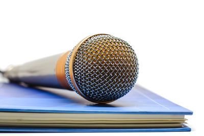 A close-up of a microphone on top of a blue book symbolizing literary news and author announcements.