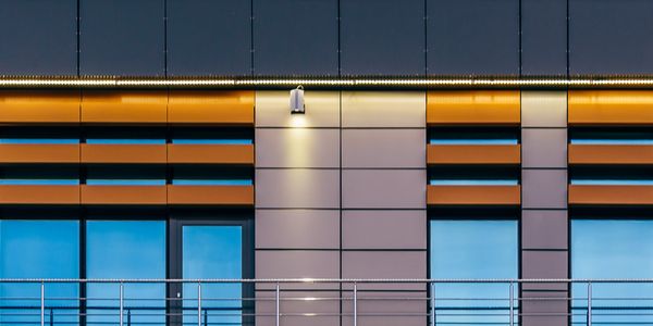 Modern building facade with blue windows and orange panels.