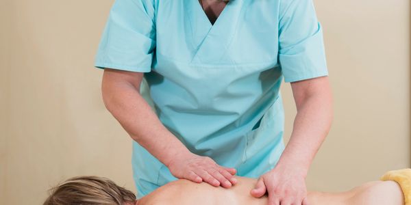 Therapist giving a back massage to a relaxed client on a massage table.