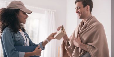 Woman giving a gift to a man wrapped in a blanket.