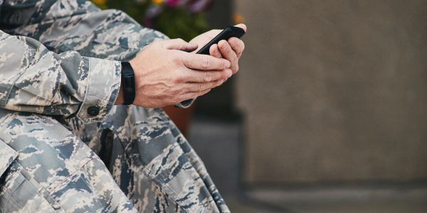 Soldier in camouflage using a smartphone.