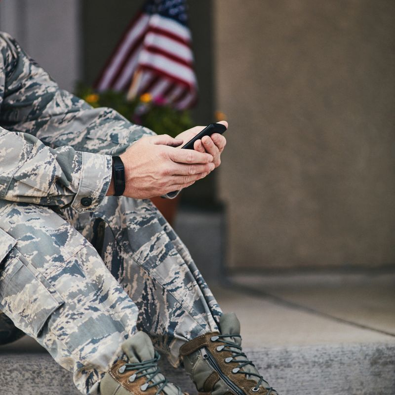 Military service member checking data on phone from fitness tracker