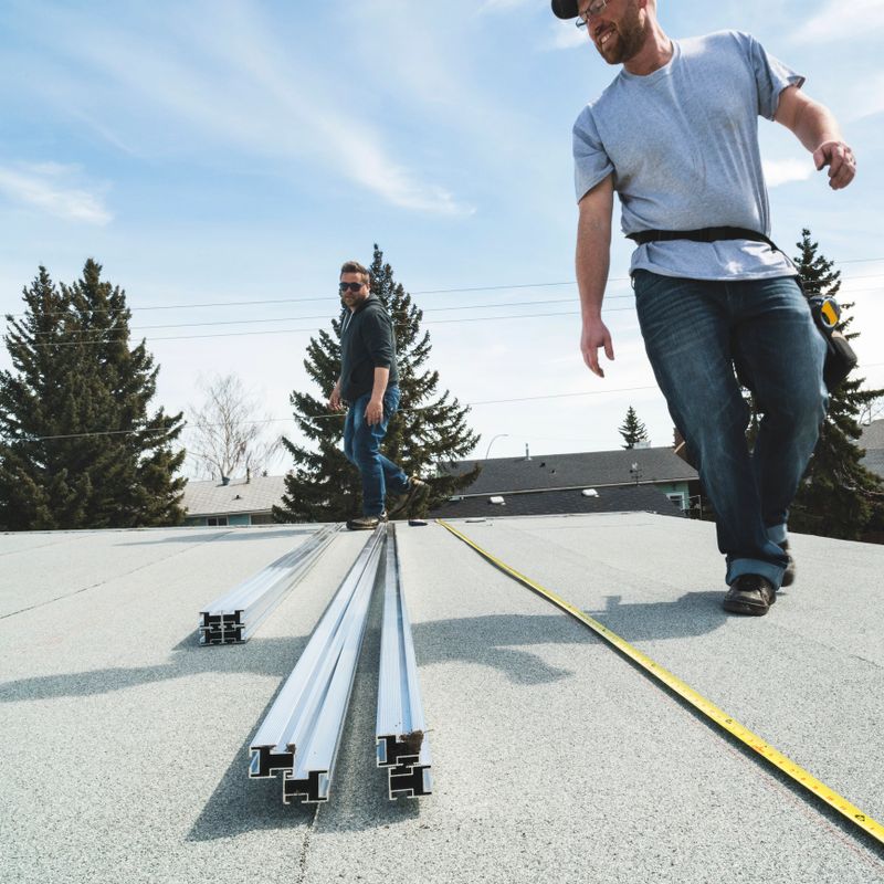 Workers measuring the layout of the module array of solar panels on a residential homes roof.