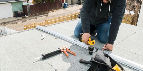Person using a drill while working on a roof installation.