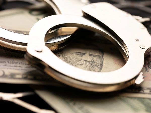 Handcuffs placed on U.S. currency, symbolizing financial crime or corruption.