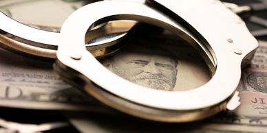 Handcuffs placed on U.S. currency, symbolizing financial crime or corruption.