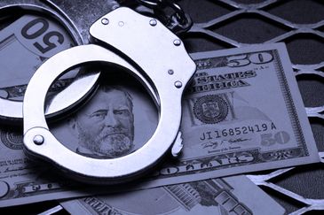 Handcuffs on top of a fifty-dollar bill.