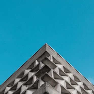 Sharp corner of a concrete building against clear blue sky.