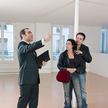 Couple viewing an empty apartment with a real estate agent.
