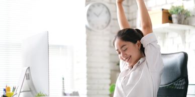 Woman stretching happily at her desk.