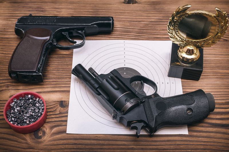 Best shooter award background with copy space. Winner in shooting. Gun, paper target and gold medal. Shooting range.