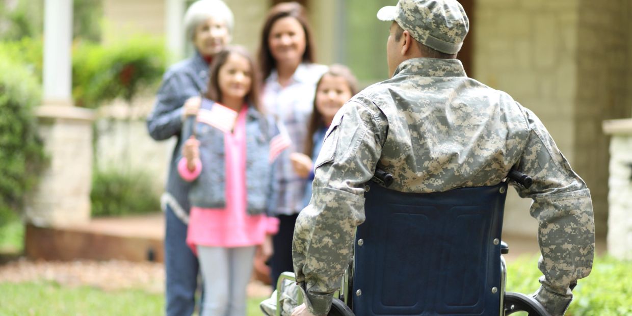 Soldier in wheelchair reunited with family outdoors.