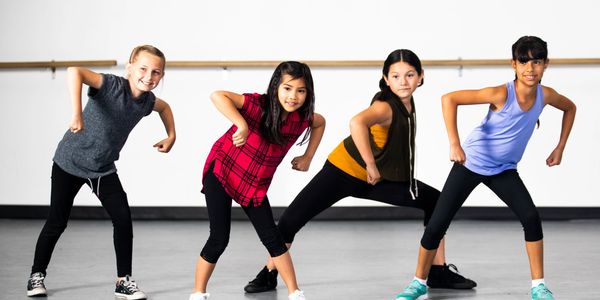 Young ballerinas stretching in a dance studio, focusing on flexibility exercises.
