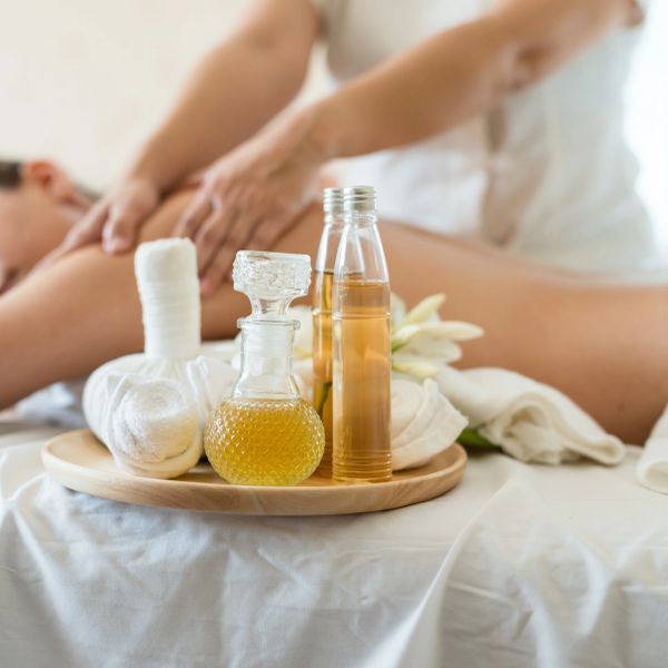 Massage oils and spa essentials with person receiving massage.