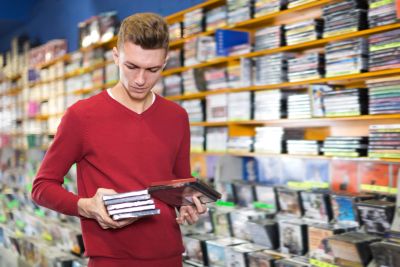 Man holding DVDs in a store.